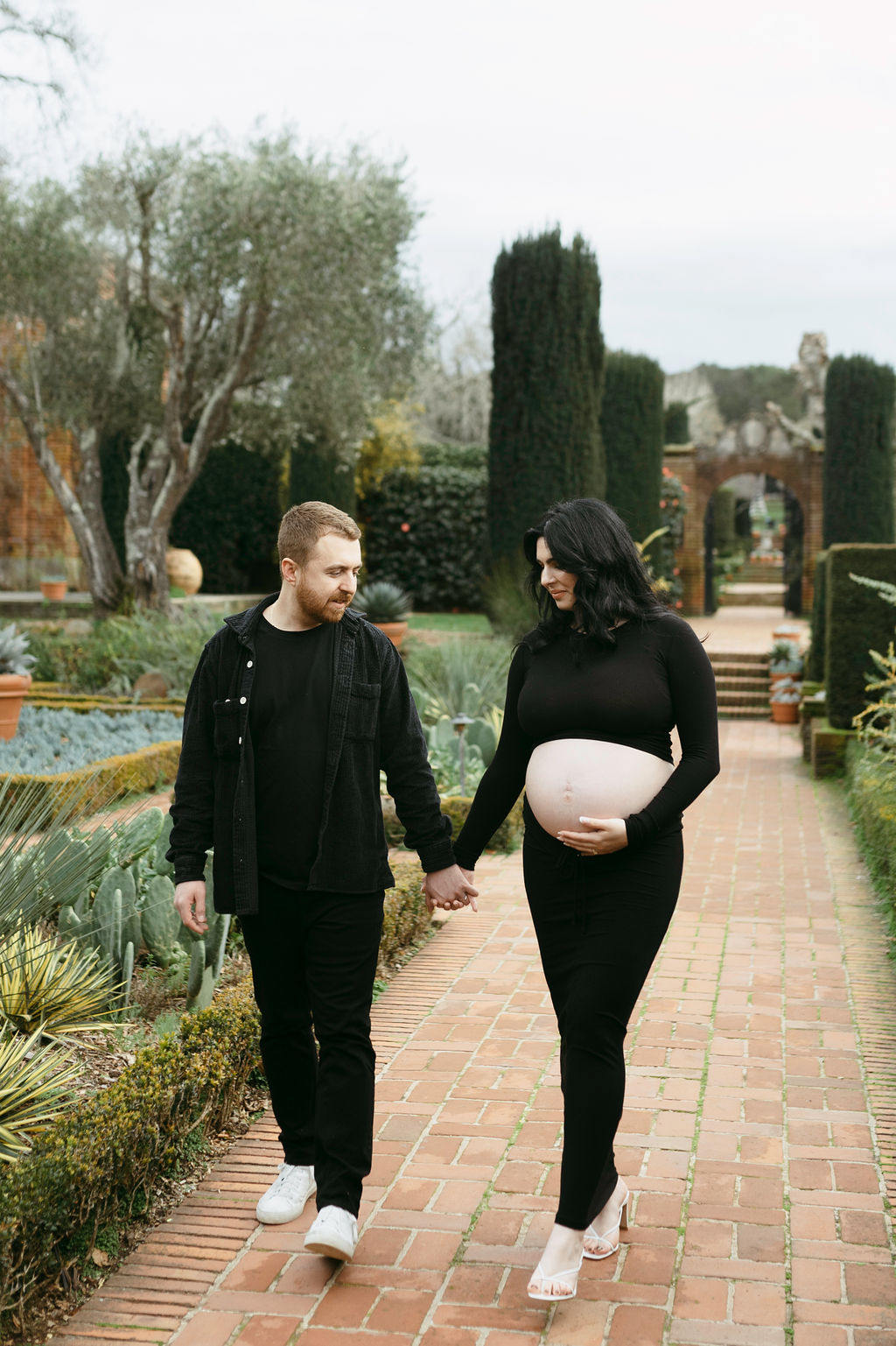 couple posing for their maternity pictures in a romantic garden in California