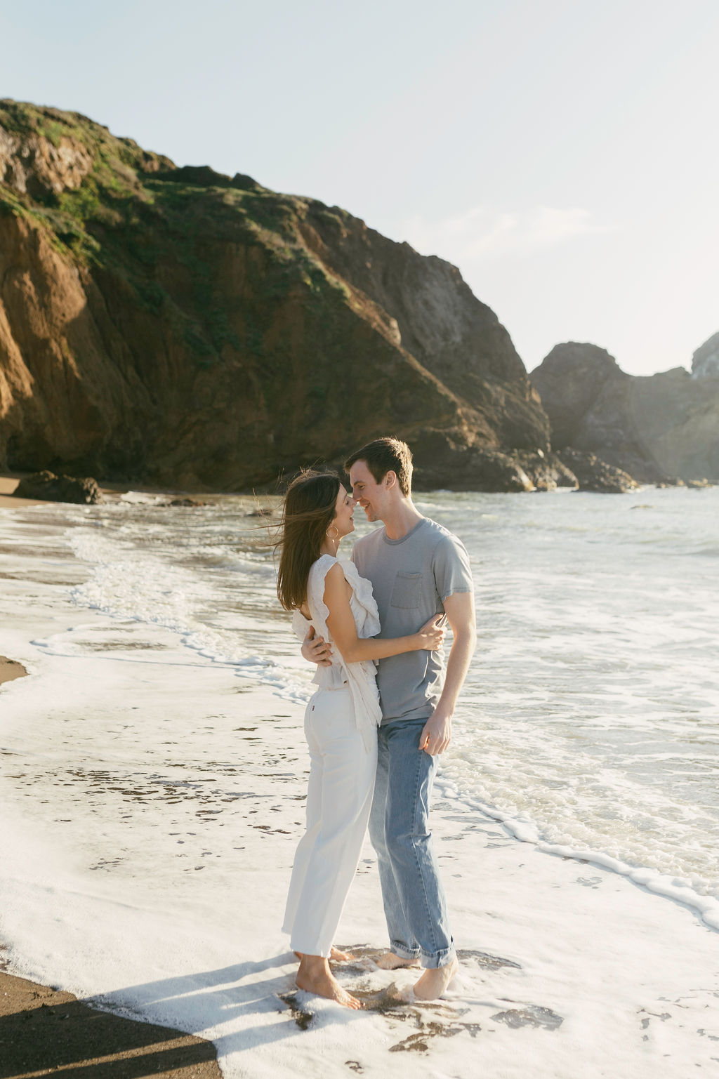 couple posing and hugging for a beach sunset engagement session during golden hour