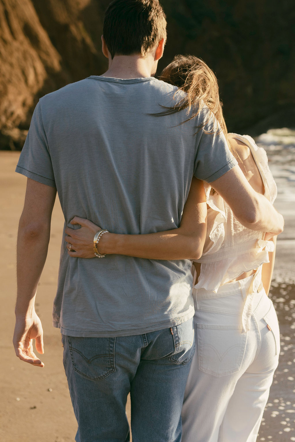 couple posing and hugging for a beach sunset engagement session during golden hour
