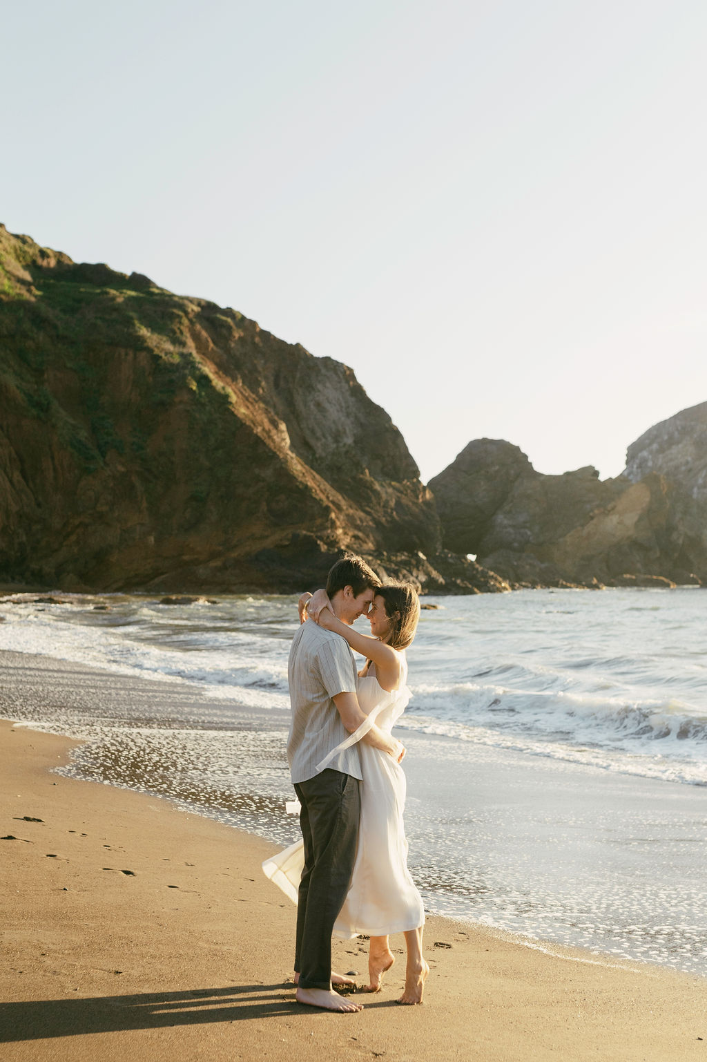 couple posing for their playful beach engagement photos on rodeo beach