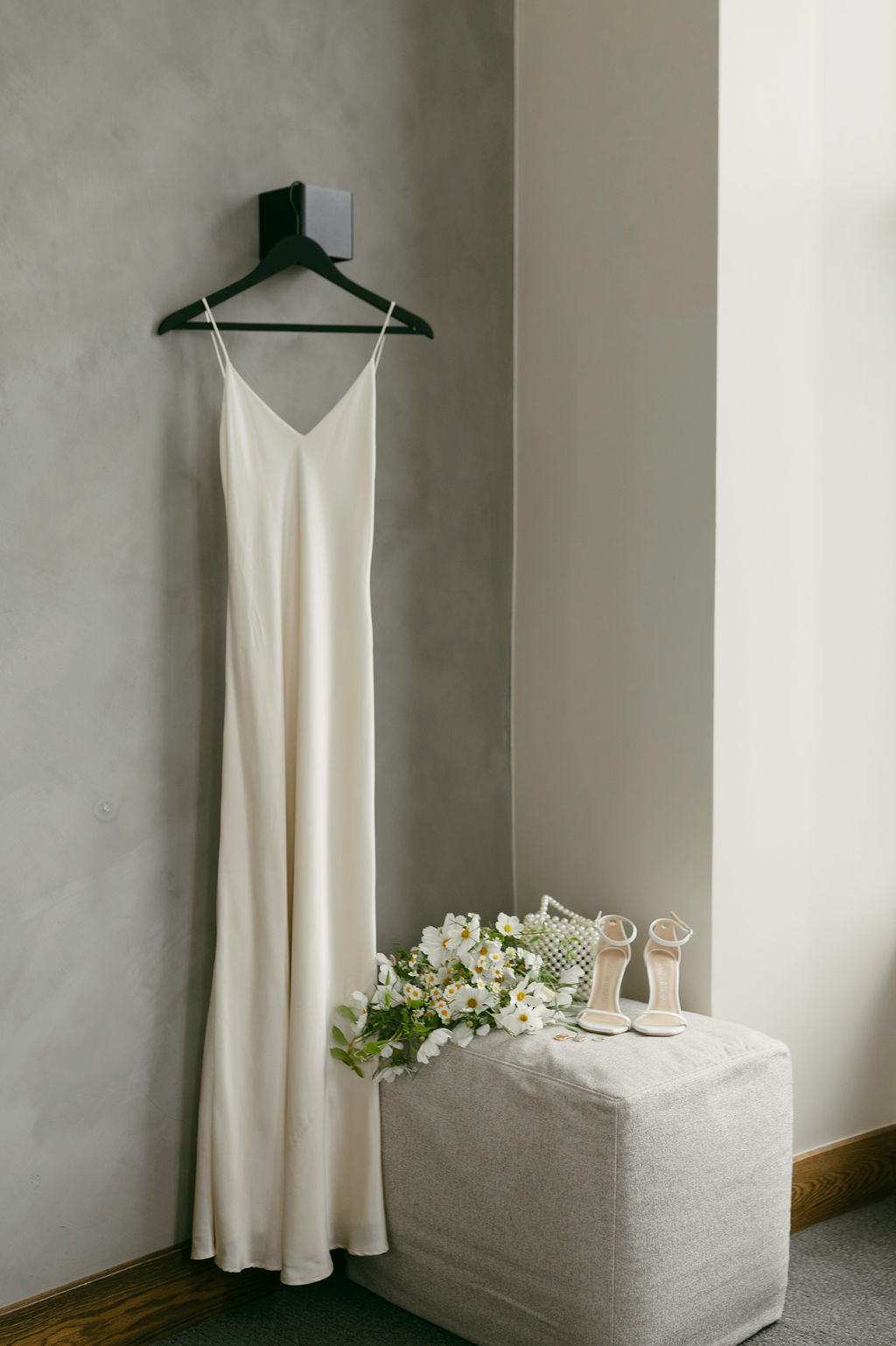 wedding dress hanging up with flowers and shoes